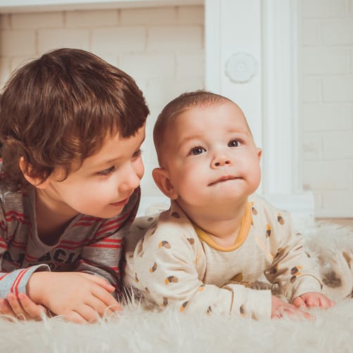 Zwei Kinder, liegend auf einem Teppich